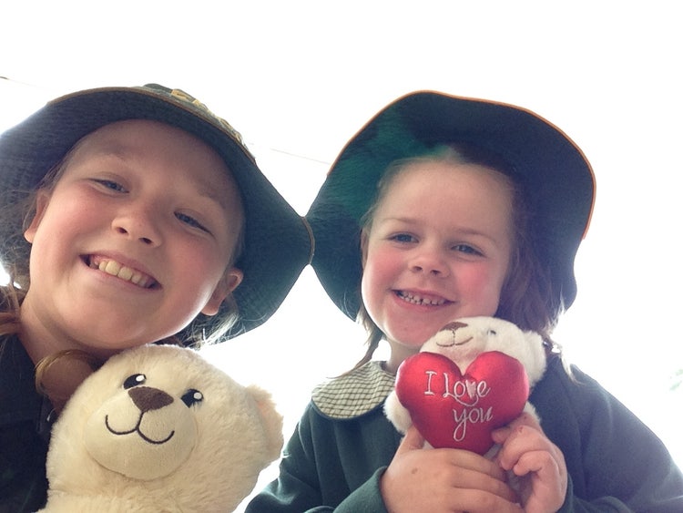 A year 6 girl with her kindy buddy, both are holding teddy bears
