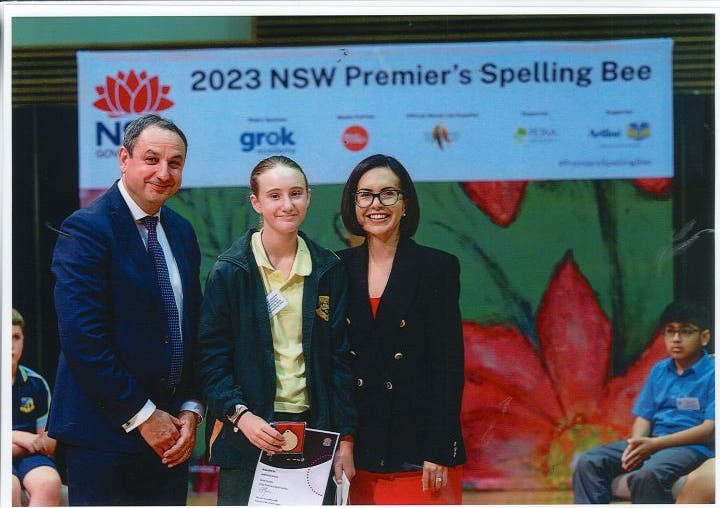 A student who made it to the state spelling bee competition. She is pictured with the Minister of Education and Secretary of Education