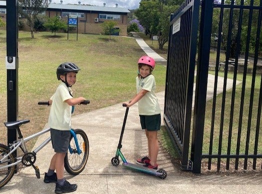 a girl riding a scooter and a boy riding a bike to school